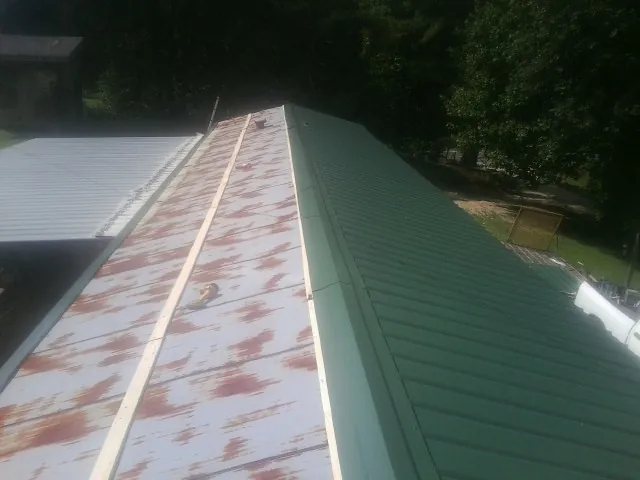 Old rusted panels beside newly installed green metal roofing — Wind Damage Roof Repair by Roofing Brothers in Shavertown