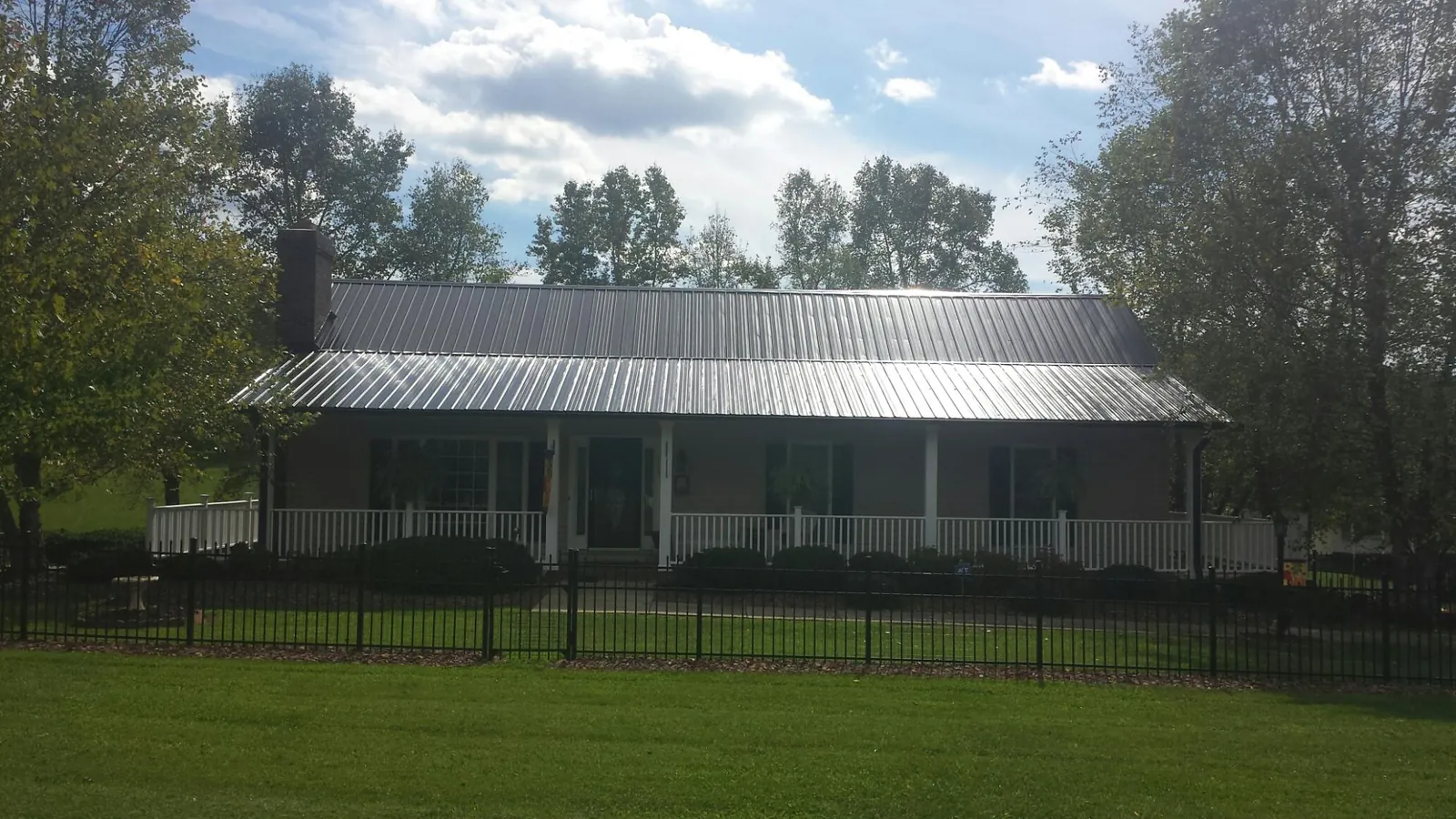 Gray metal roof on a brick ranch with a full width front porch — Gutter Guard Installation work by our crew in Shavertown