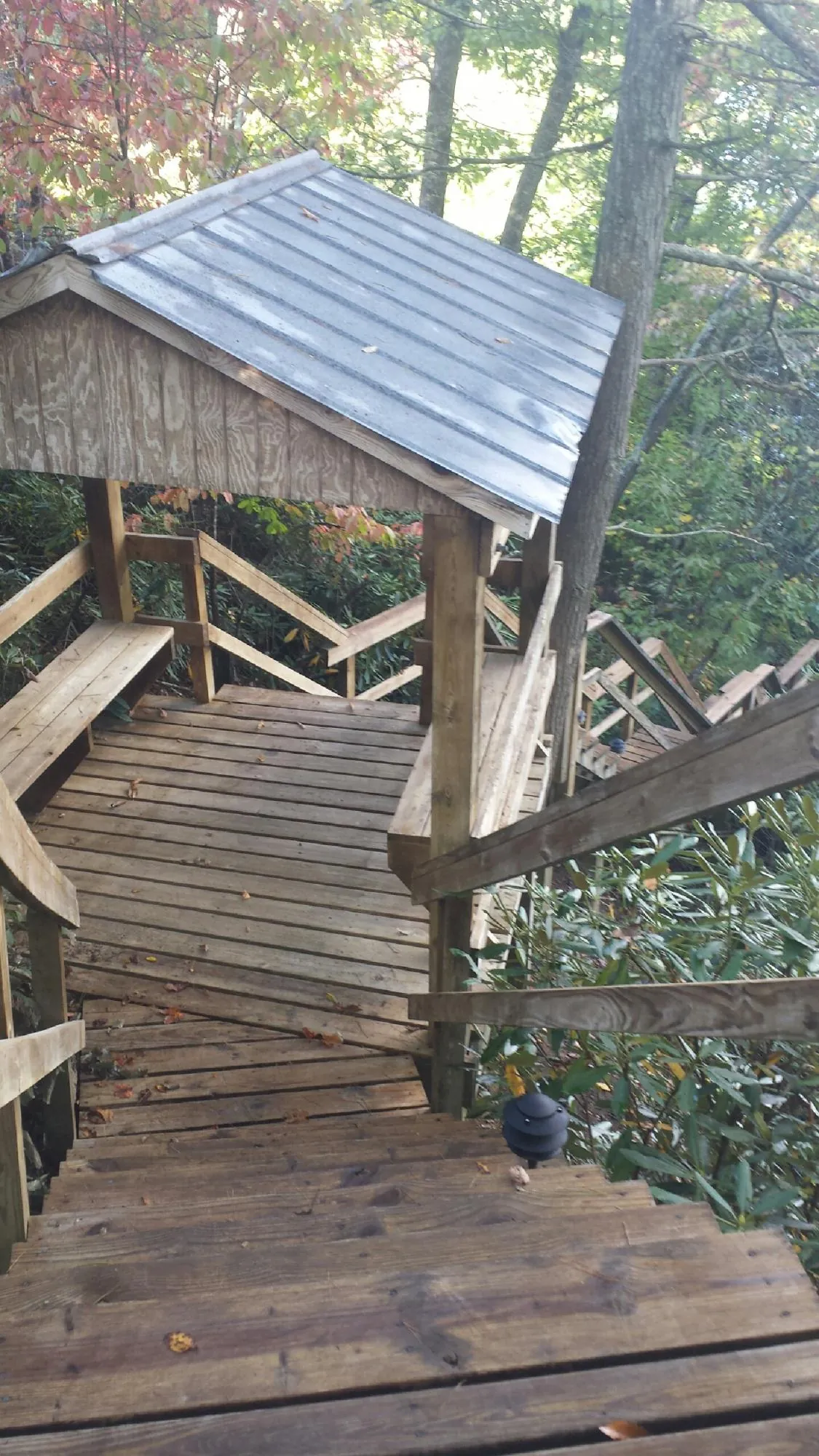Metal roofed shelter over wooden steps on a wooded walkway — Skylight Repair & Installation work by our crew in Shavertown
