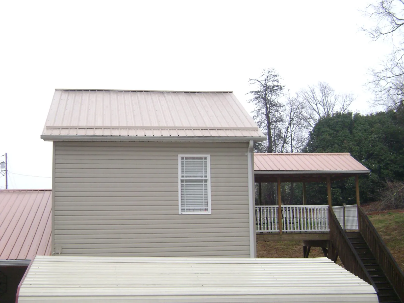Tan metal roofs on a two story addition and attached porch, from a Roof Replacement job in Shavertown