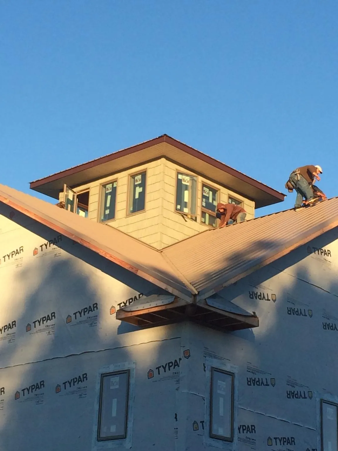Roofers working around a rooftop cupola on a new metal roof at sunset — Roof Waterproofing in Shavertown by Roofing Brothers